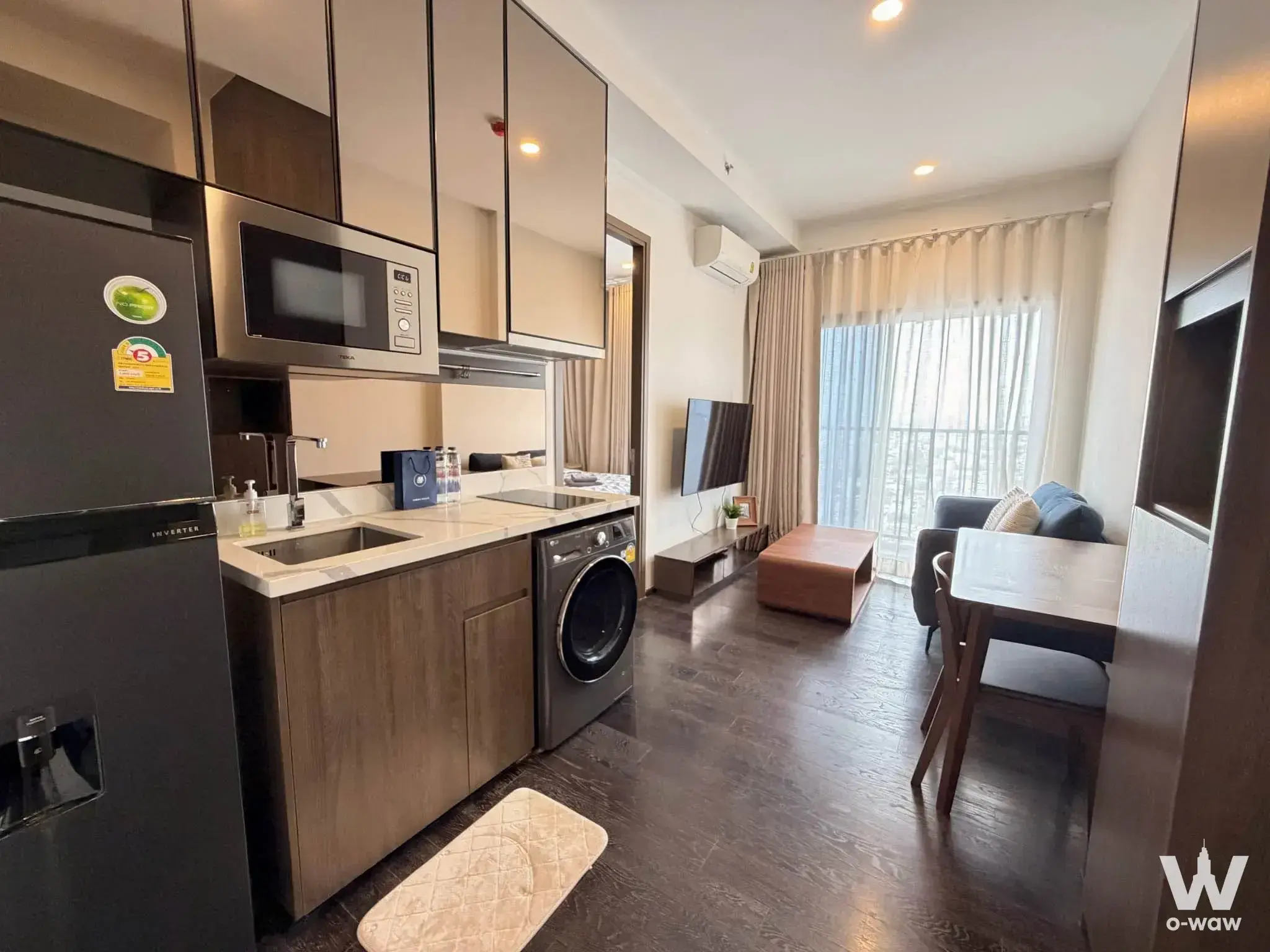 Fully furnished 1-bed condo studio in Park Origin Thonglor with dark wood floors, integrated kitchenette, and balcony access