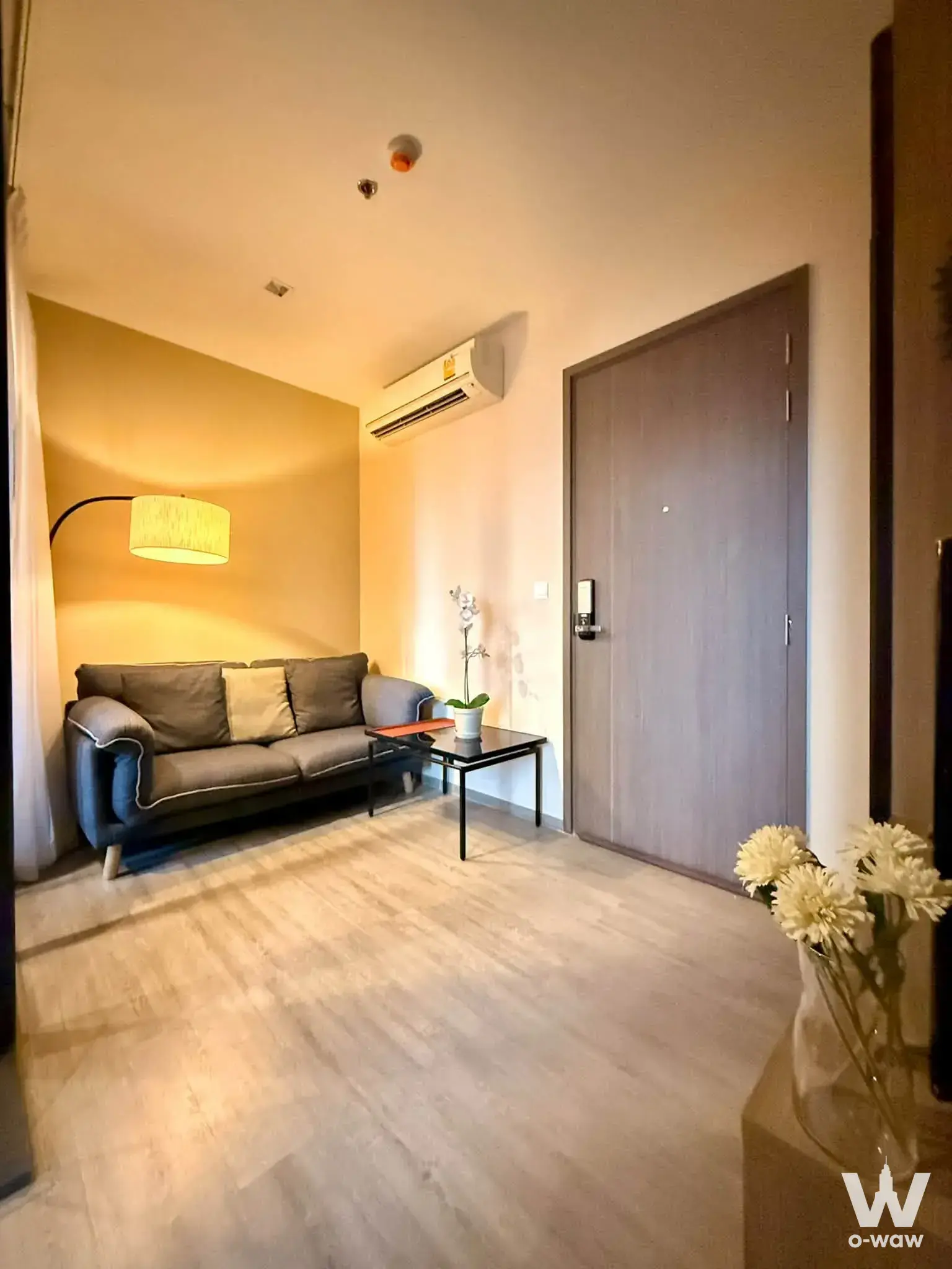 Furnished 1-bed condo living room in THE LINE Wongsawang with dark-grey sofa, mustard yellow accent wall