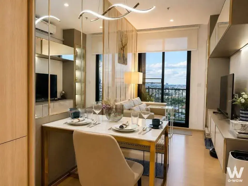 Luxury dining area in a MARU Ekkamai 2 2-bed rental showcasing a marble table, gold accents, and wavy LED chandelier overhead
