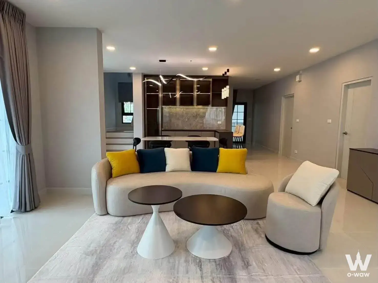 Centro Bangna 4-bed house living room features curved beige sofa and dark wood kitchen bar