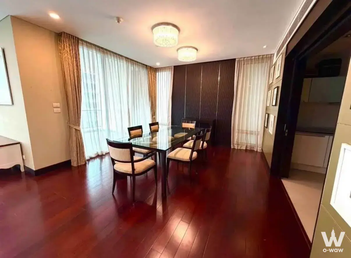 Dining area in a 3-bed condo for rent at The Park Chidlom with a glass table and crystal chandeliers