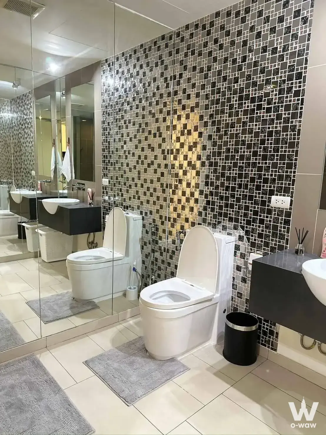 Modern bathroom in Zire Wongamat featuring a black mosaic accent wall, floating vanity, and floor-to-ceiling glass partition