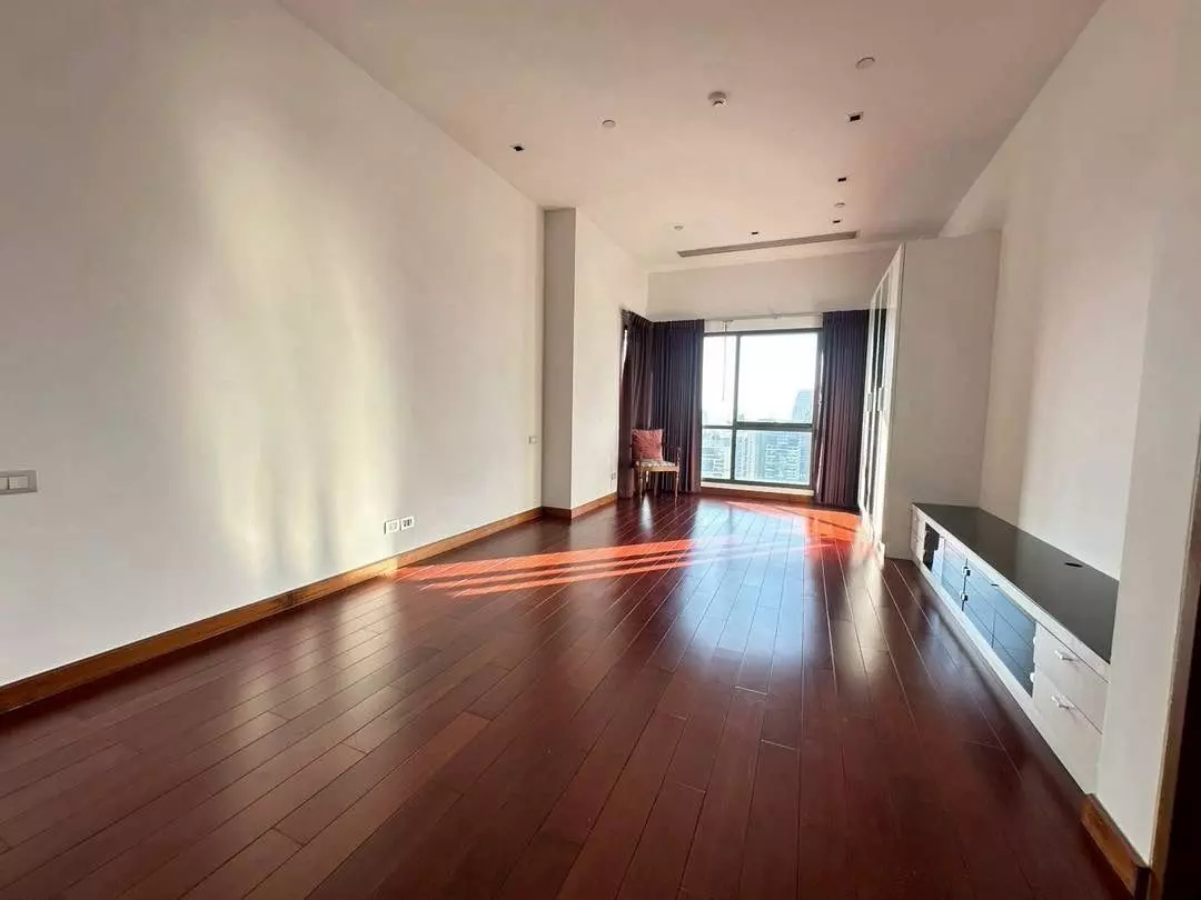 Spacious empty living room in Le Raffine Sukhumvit 39 with hardwood floors and city view