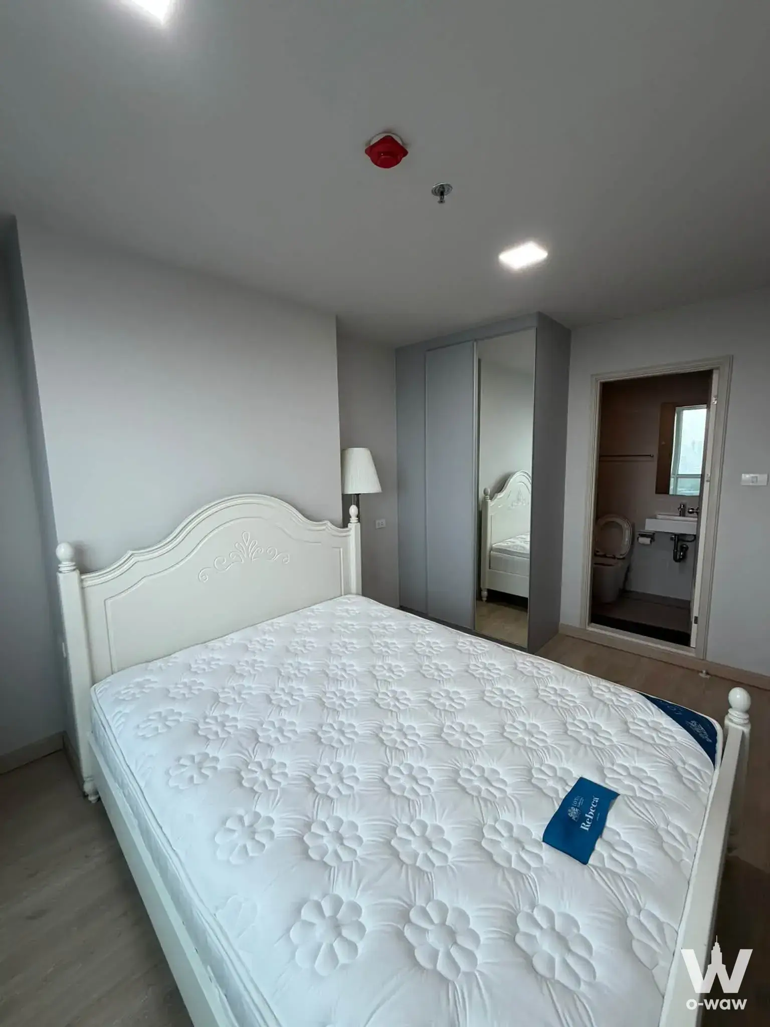 White ornate headboard bed and mirrored wardrobe in a modern Lumpini Selected Sutthisan condo