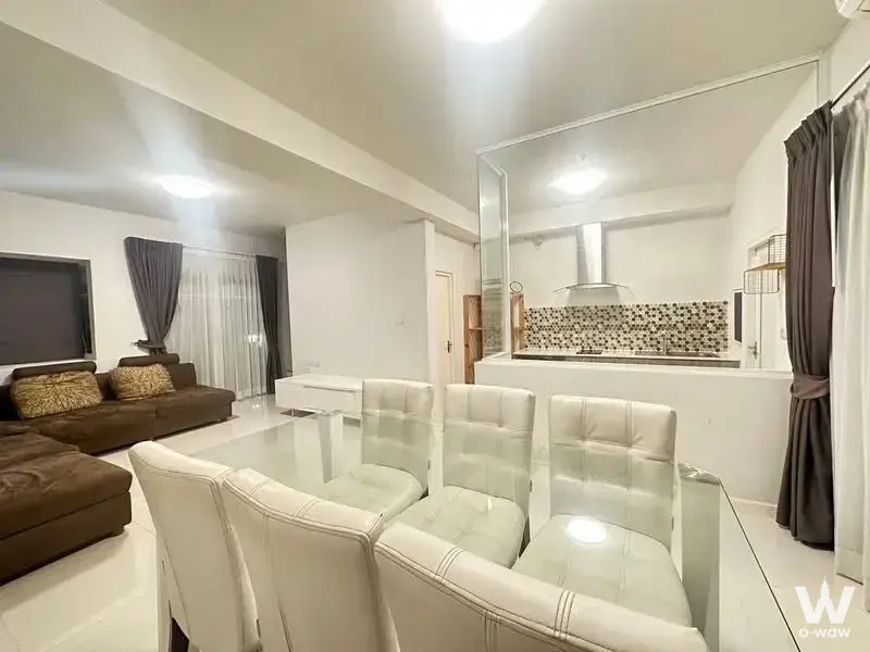 L-shaped sofa and glass dining table in an open-plan Indy 3 Bangna townhouse living area