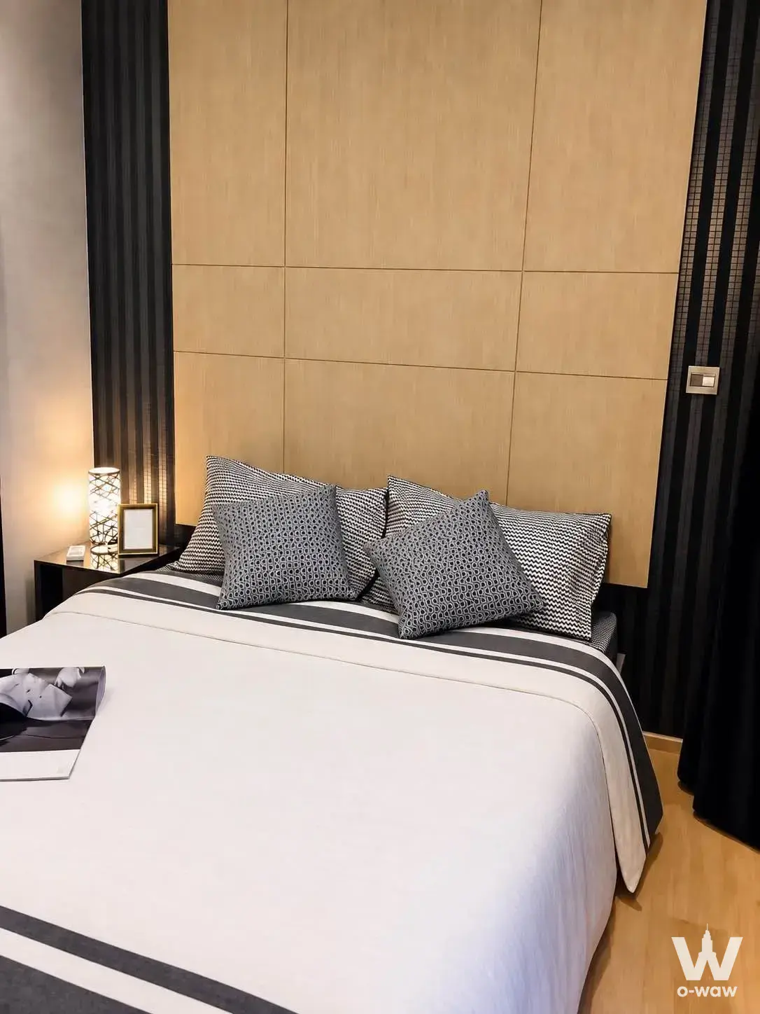 Bedroom in a 1-bed M Thonglor 10 condo for rent with a queen bed and light wood panel headboard