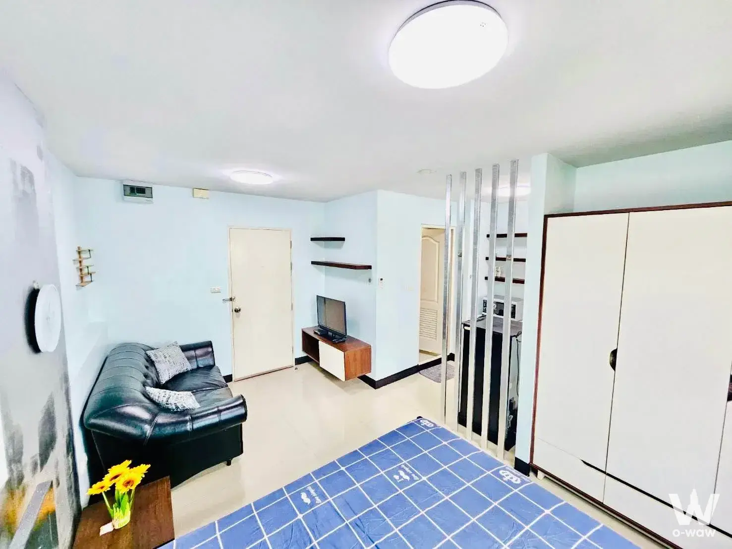 Studio living area with black sofa and sunflowers in this furnished 1-bed condo for sale at The Spring Condo