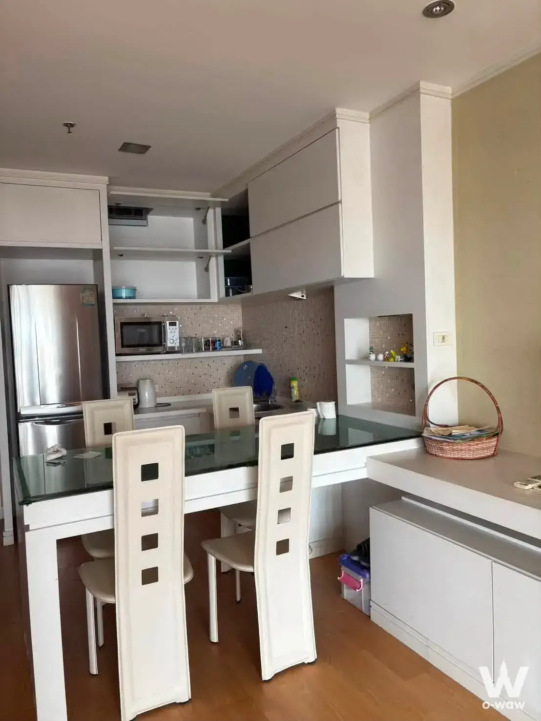 Open plan kitchen and dining area in a St Louis Grand Terrace condo with white cabinets and glass table