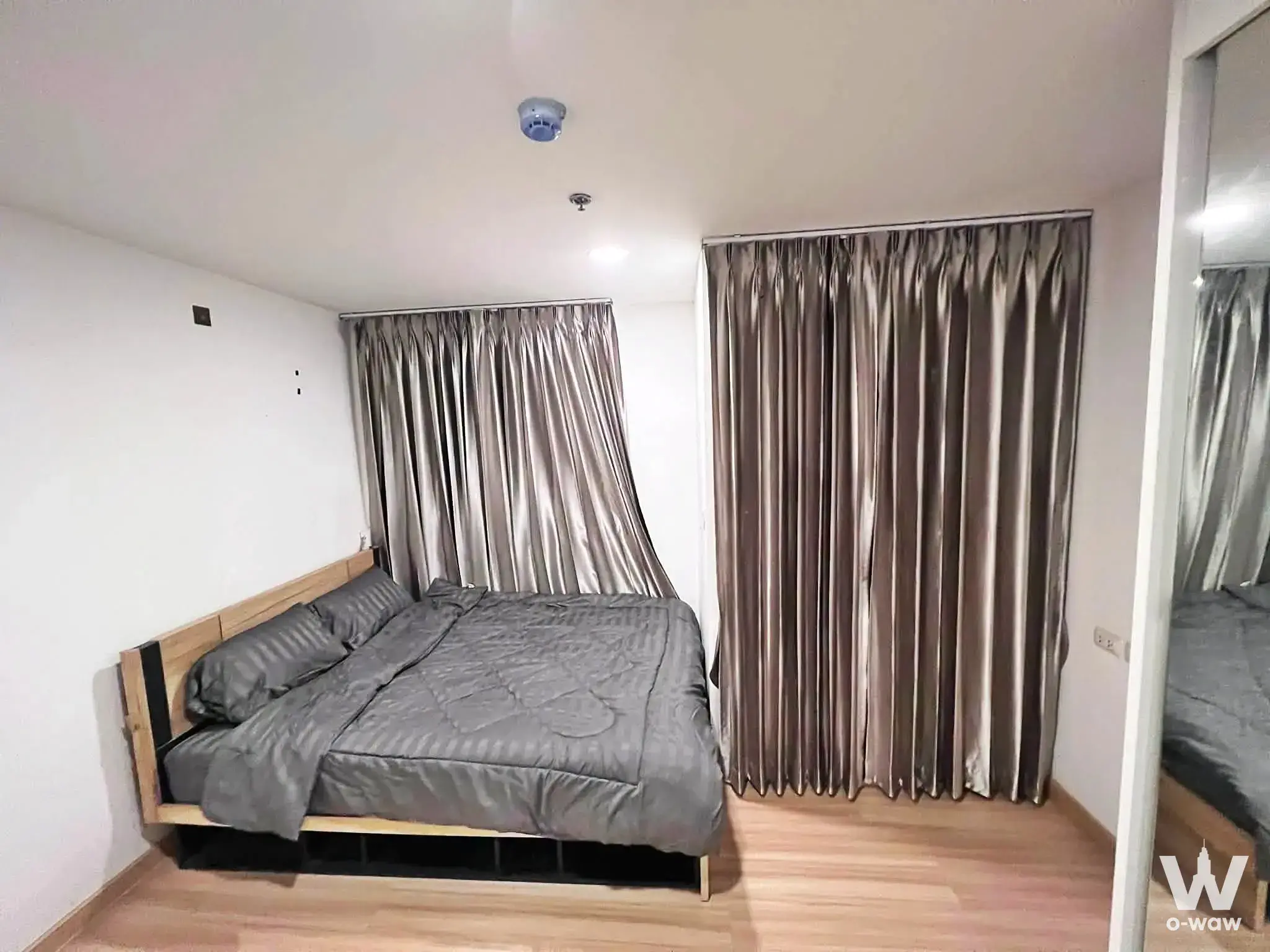 Chateau in Town Rama 8 bedroom with light wood bed, bronze blackout curtains, and mirrored wardrobe