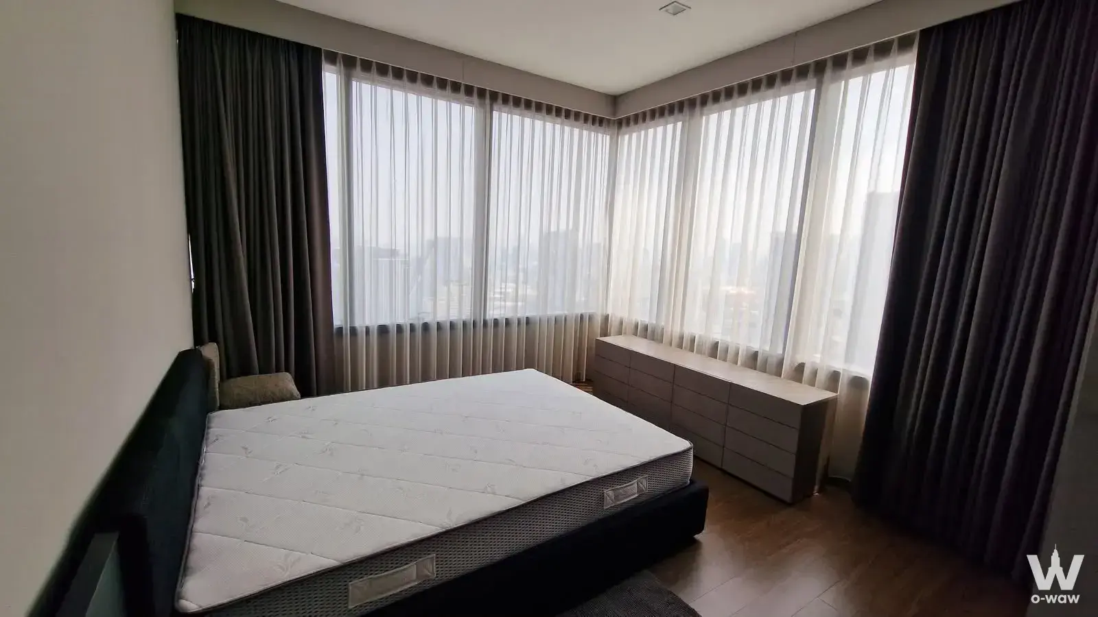 Spacious M Silom bedroom with floor-to-ceiling windows offering a city skyline view