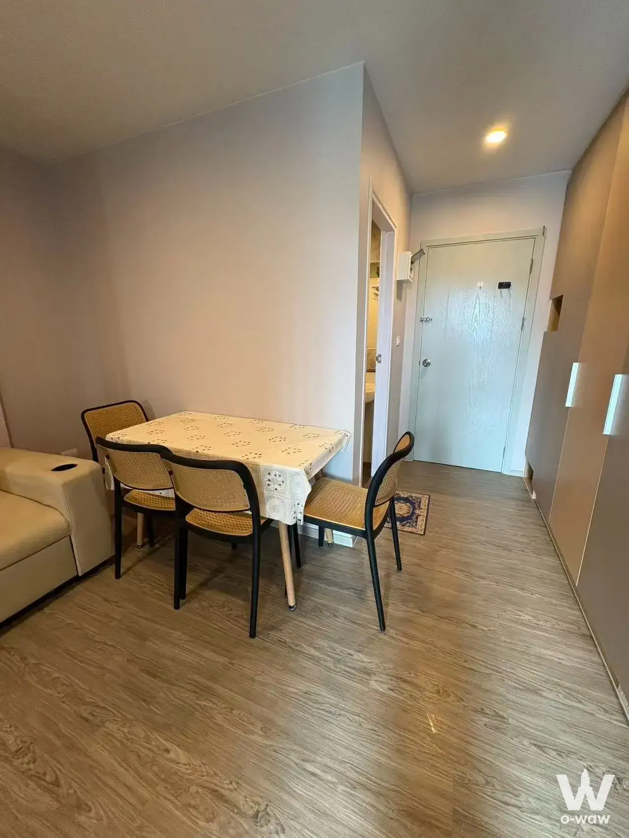 Dining area in a Regent Home Bangna 1-bed condo featuring light wood laminate flooring and cane-back chairs