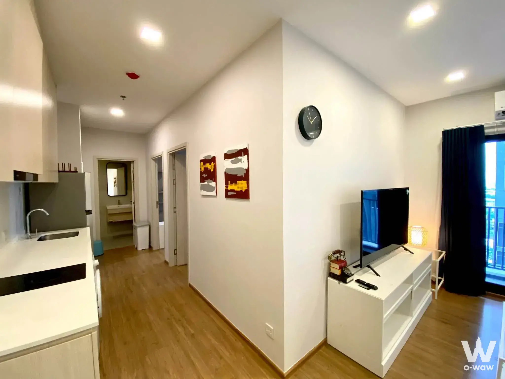 Open-plan living area in a 2-bed Metris Rama 9 condo featuring white kitchenette and TV console