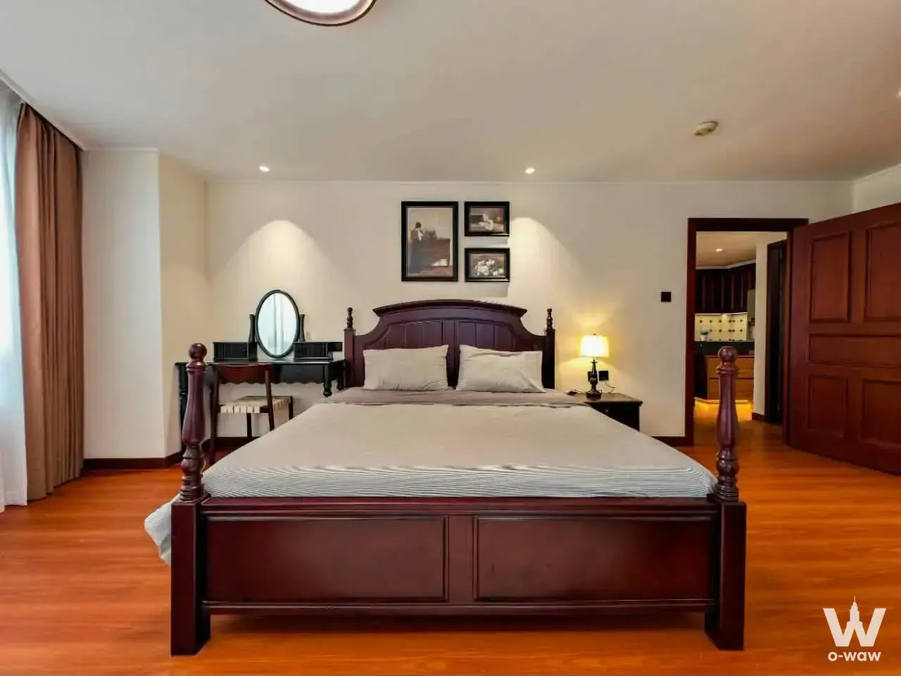 The classic bedroom of a 2-bed Jomtien Plaza Residence condo has a mahogany four-poster bed, vanity and open bathroom doorway