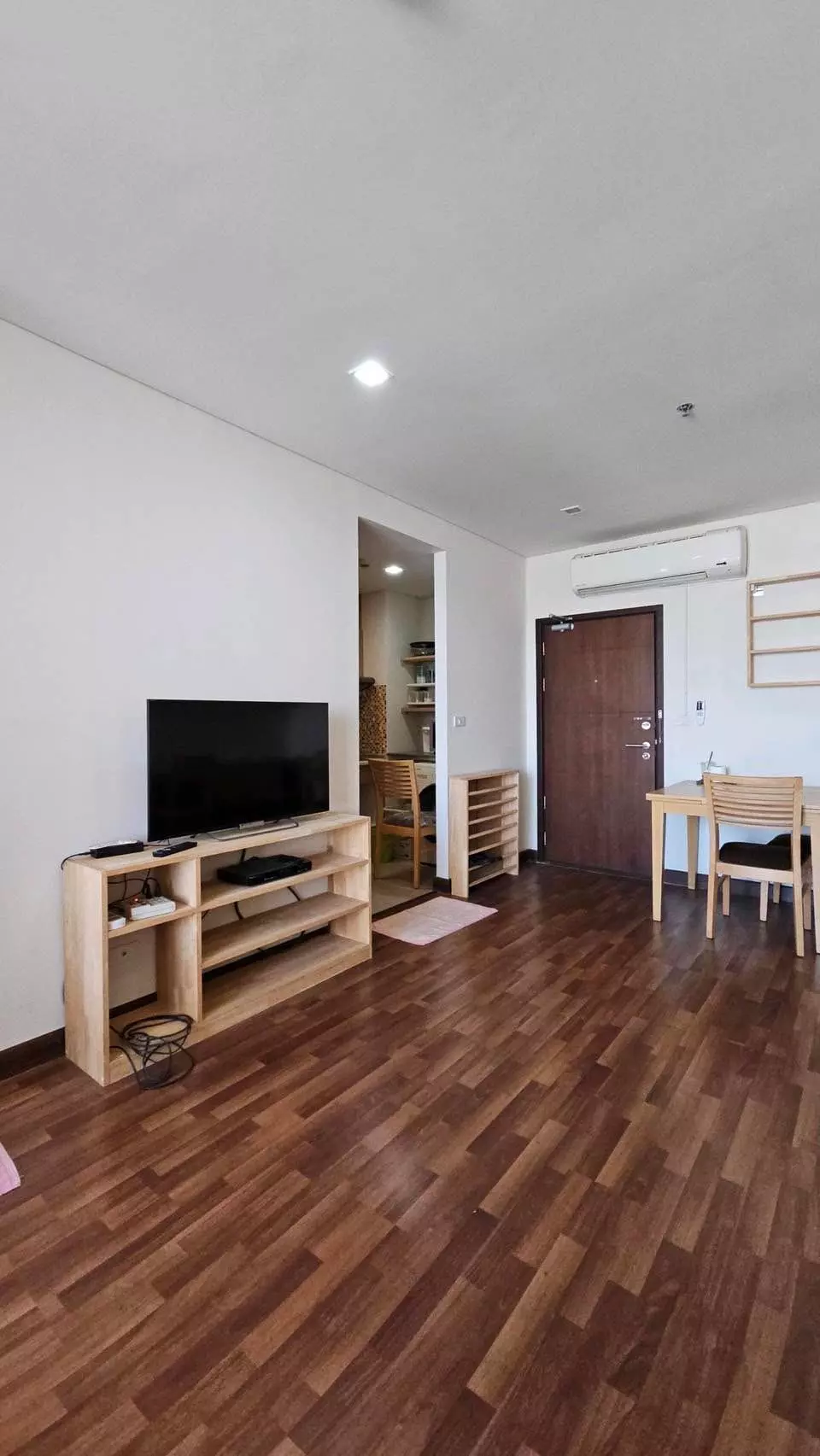 Le Luk Condominium 1-bed condo open-plan living area with oak media console and dining set