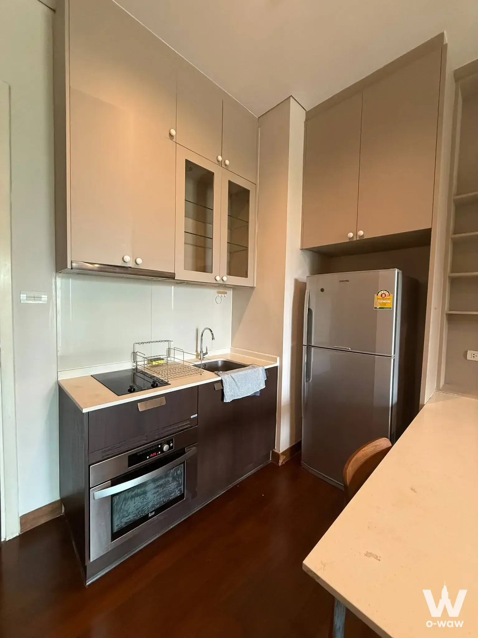 Modern kitchen in an IVY THONGLOR 1-bed condo with beige cabinets, stainless steel appliances, and dark wood-grain lower