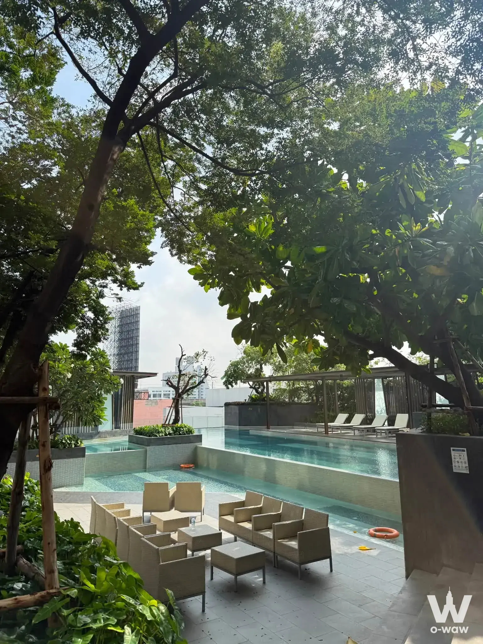 Resort-style pool terrace with turquoise water and wicker seating at Nich Pride condo for rent in Thong Lor