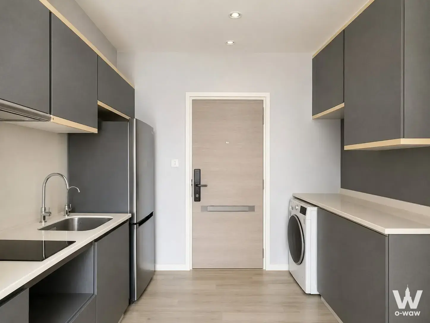 Galley utility kitchen with dark grey matte cabinetry and light wood trim in a 1-bed condo for sale at The Key