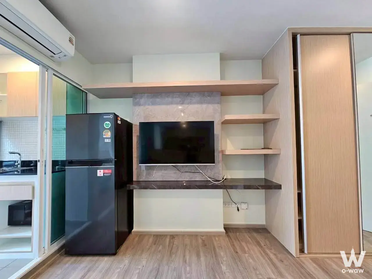 Living room in Regent Home Bangna with wall-mounted TV and light wood cabinetry