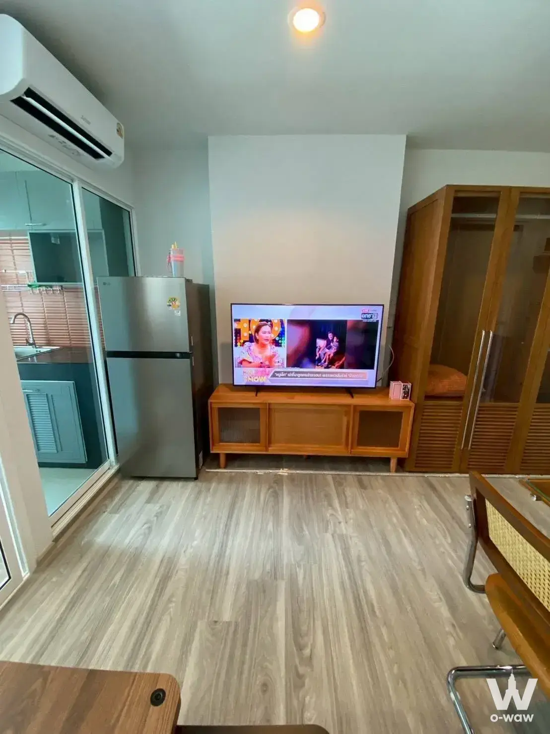 Furnished living room in a Regent Home Bangna condo with laminate floors and a sliding glass partition to the kitchenette
