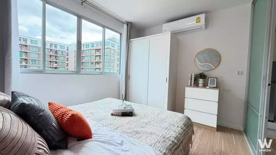 Queen bed with burnt-orange pillows in a Dcondo Kathu Patong bedroom featuring oak floors and large sliding windows
