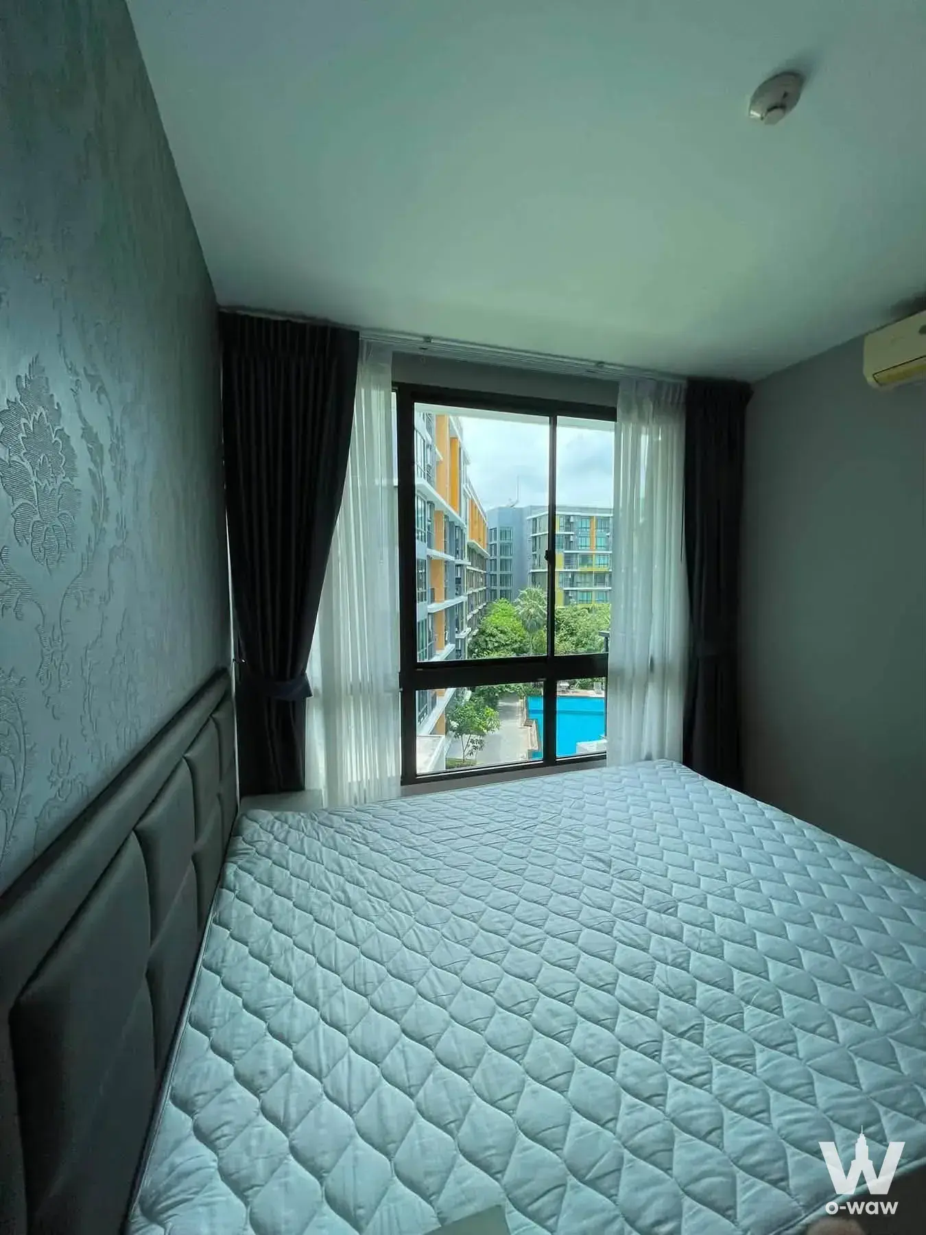 Bedroom in iCondo Sukhumvit 103 2-bed rental showing queen bed and sliding glass door to balcony