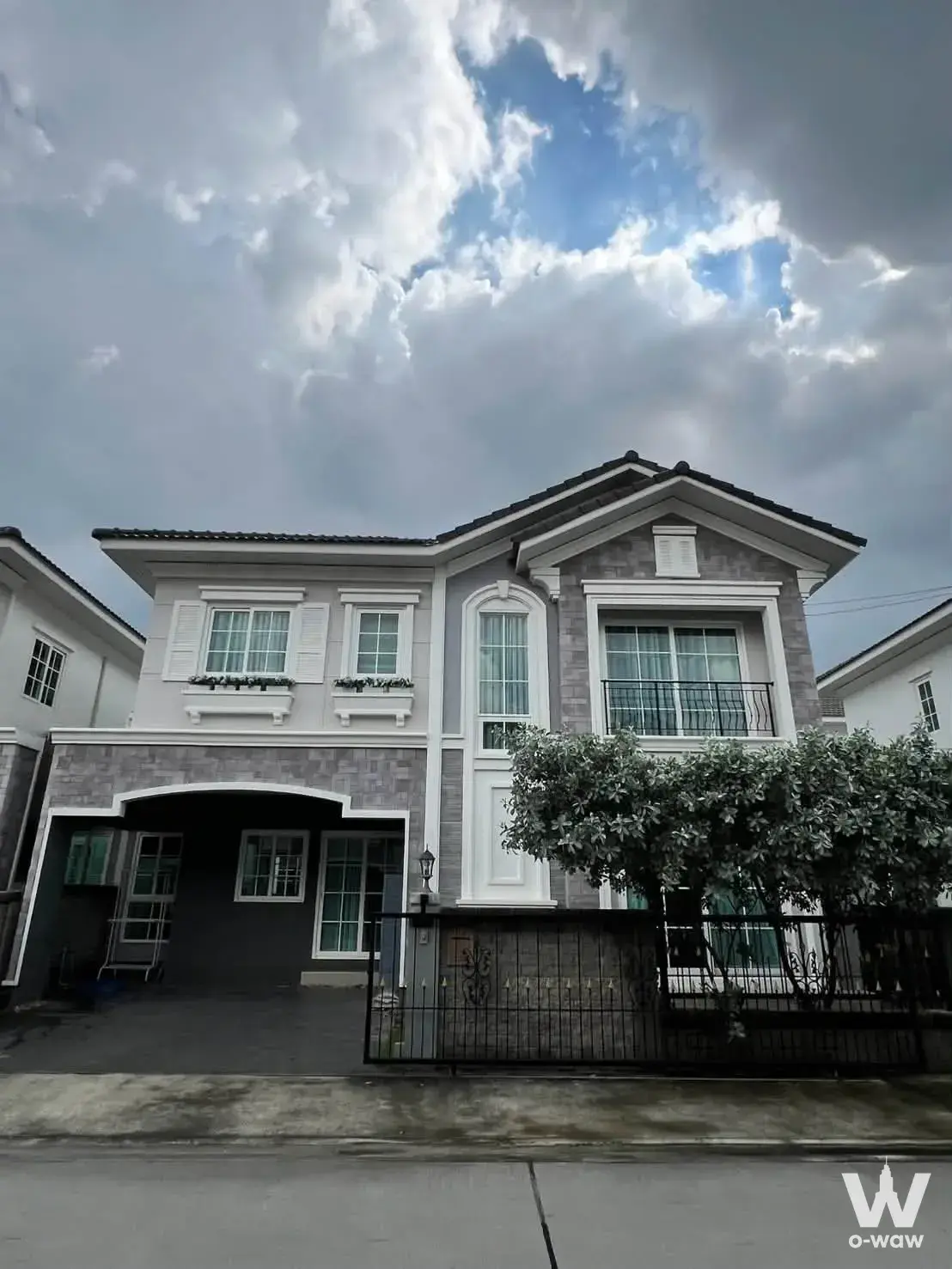 Two-story house exterior with arched carport and stone facade in Golden Neo Bangna-Suanluang