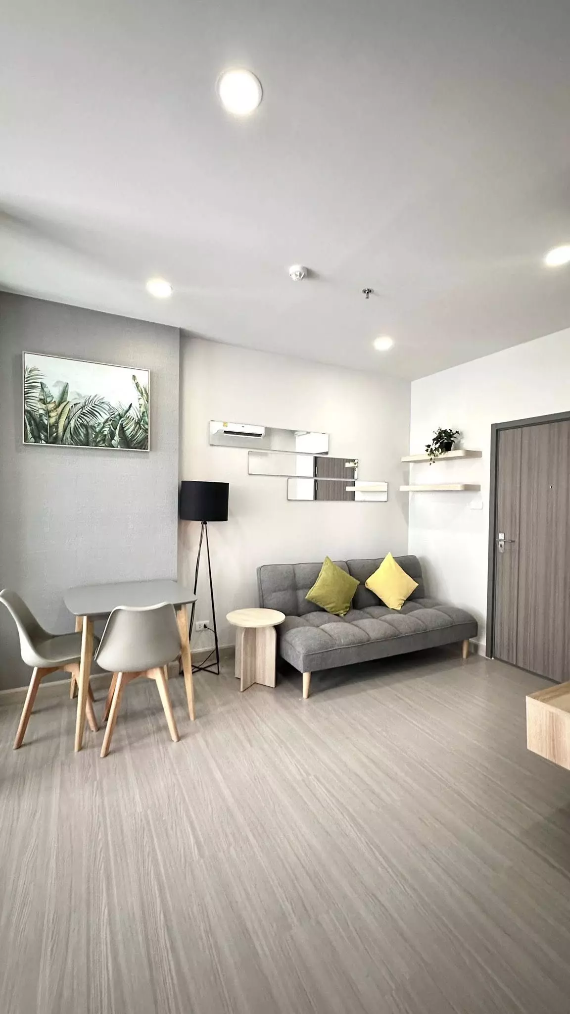 Living room in a 1-bed Supalai Loft Sathon-Ratchaphruek condo featuring grey sofa and wooden dining set