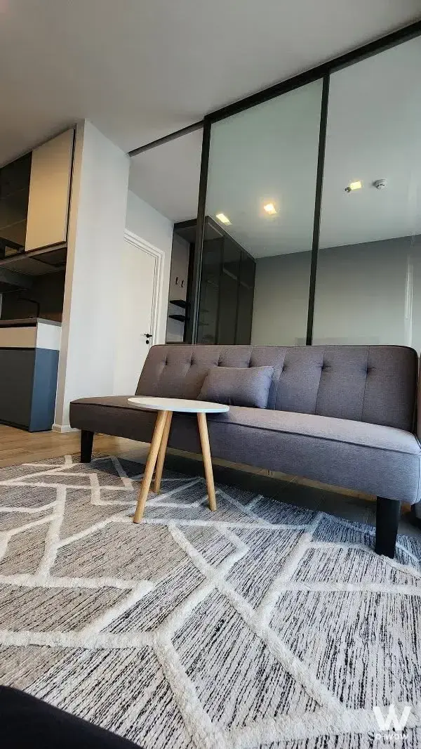 Living room in a 1-bed condo for rent at The Key Rama 3 featuring a grey tufted sofa and glass partition