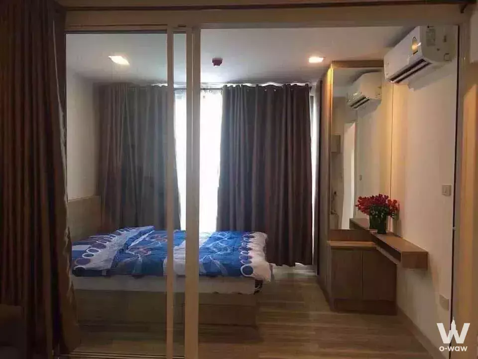 Bedroom in a Moniiq Sukhumvit 64 condo with blue duvet and floating wooden vanity desk