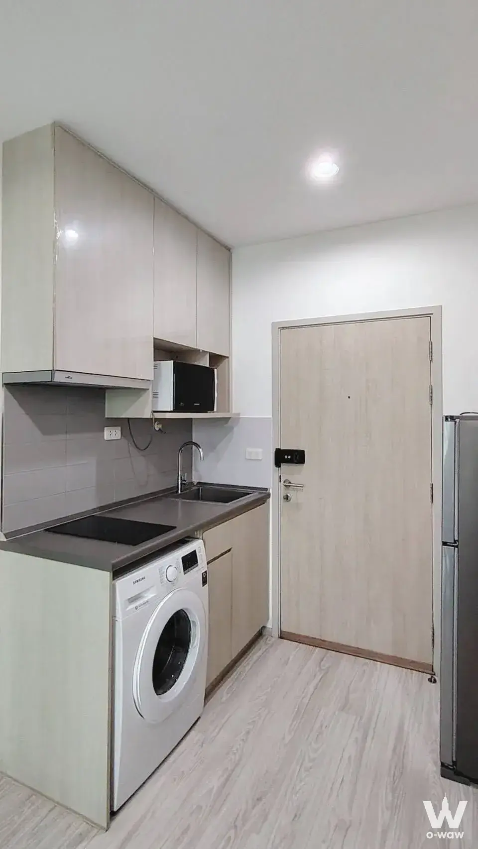 Compact kitchenette in Ideo Mobi Sukhumvit Eastgate with beige cabinets and an integrated washing machine
