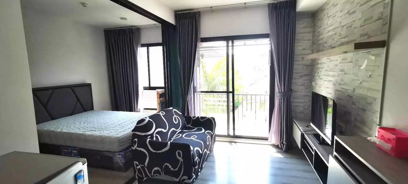 Furnished studio in Notting Hill Sukhumvit 105 with faux-stone feature wall and balcony access