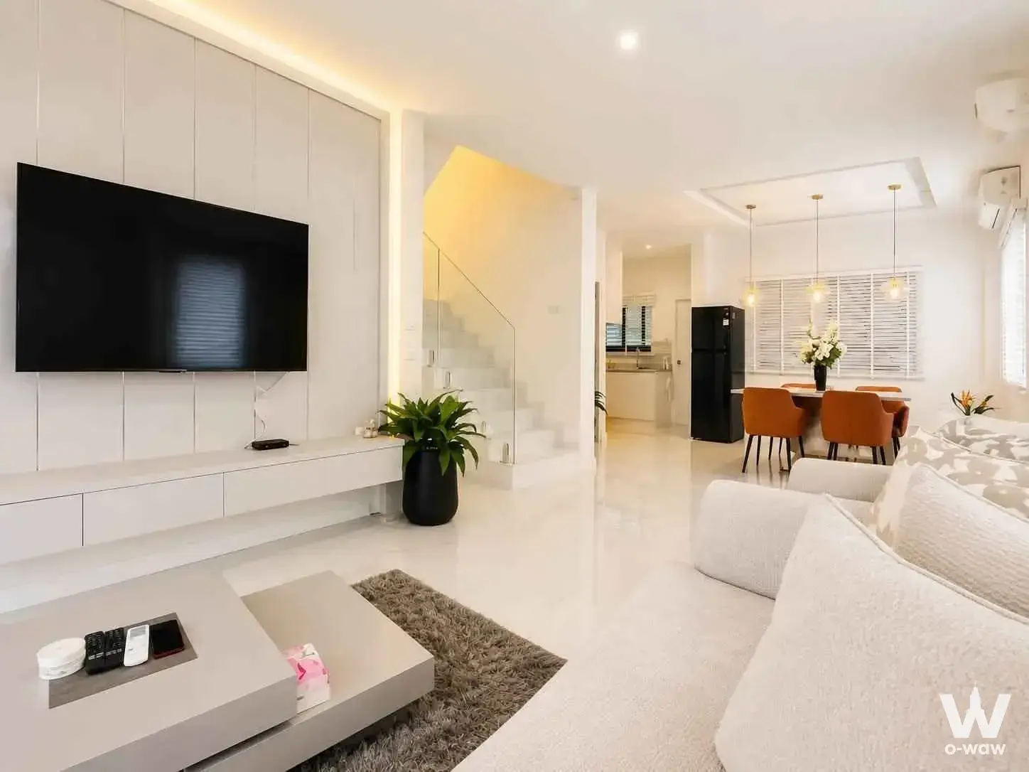 Modern 3-bed house for rent in Patta Village with open-plan living, black TV on white paneled wall, and orange dining chairs
