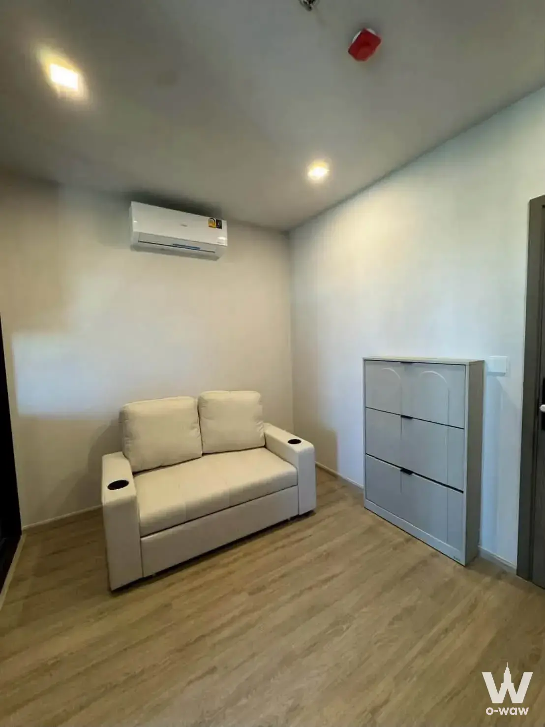 Cream sofa and grey cabinet in the compact living area of a 0-bed condo for rent at M Ladprao