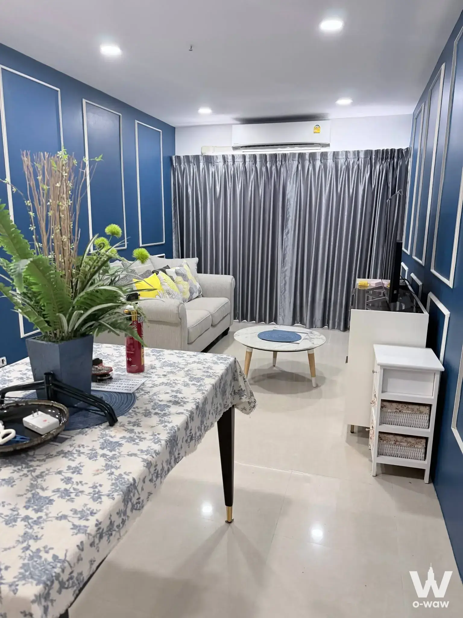 Living room in Witthayu Complex condo with navy blue walls and beige fabric sofa