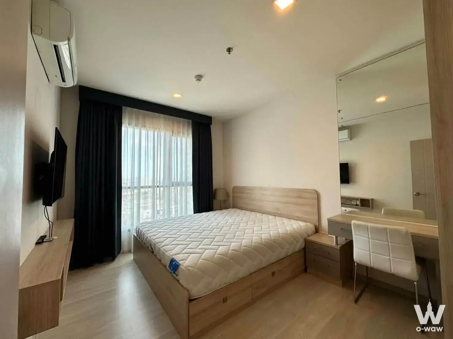 Life Sukhumvit 48 1-bed master bedroom with navy blackout curtains, wood laminate floors, and vanity desk