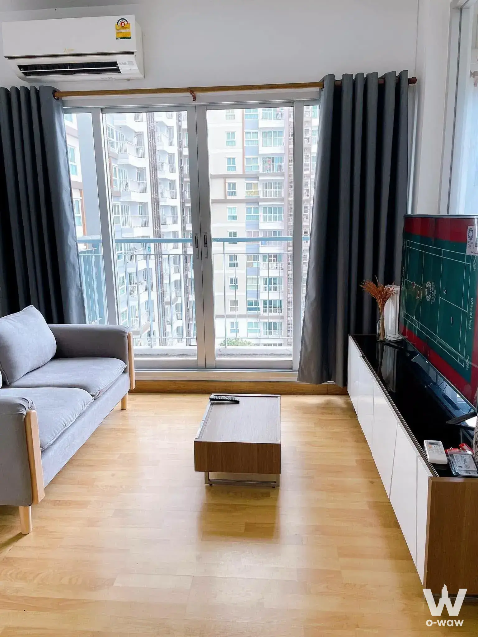 Bright living room in a 1-bed condo at The Parkland Taksin with light oak floors and floor-to-ceiling balcony doors