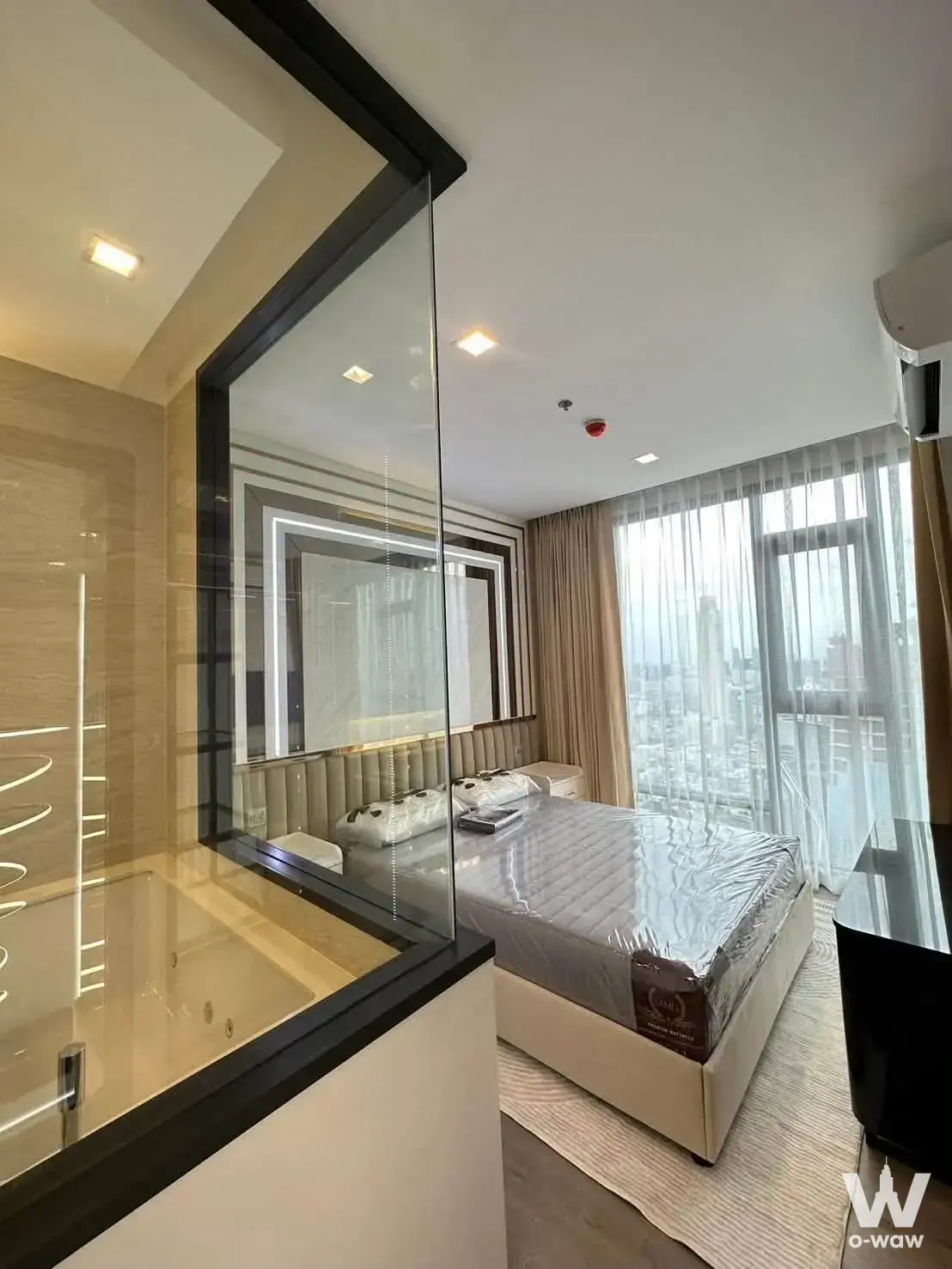 Master bedroom in a 2-bed condo for sale at The Address Siam-Ratchathewi with glass partition and city view