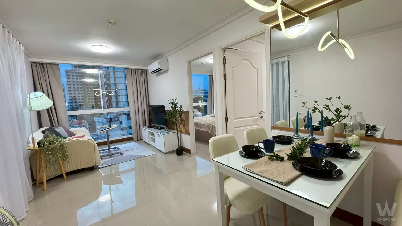 Cream sofa and glass dining table fill the open-plan living area of a furnished 1-bed unit in Chateau in Town Phahol 11