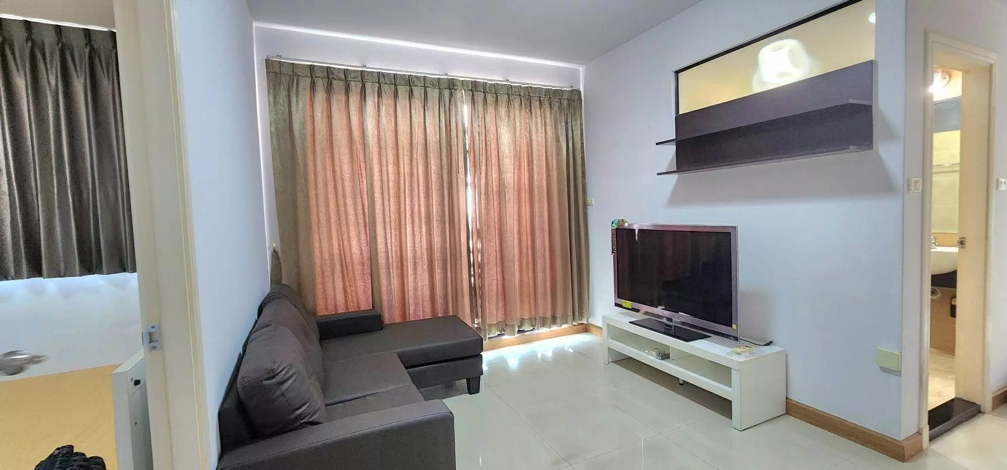 Living room in a Supalai Casa Riva Vista 1 condo with dark leather sectional and floor-to-ceiling windows