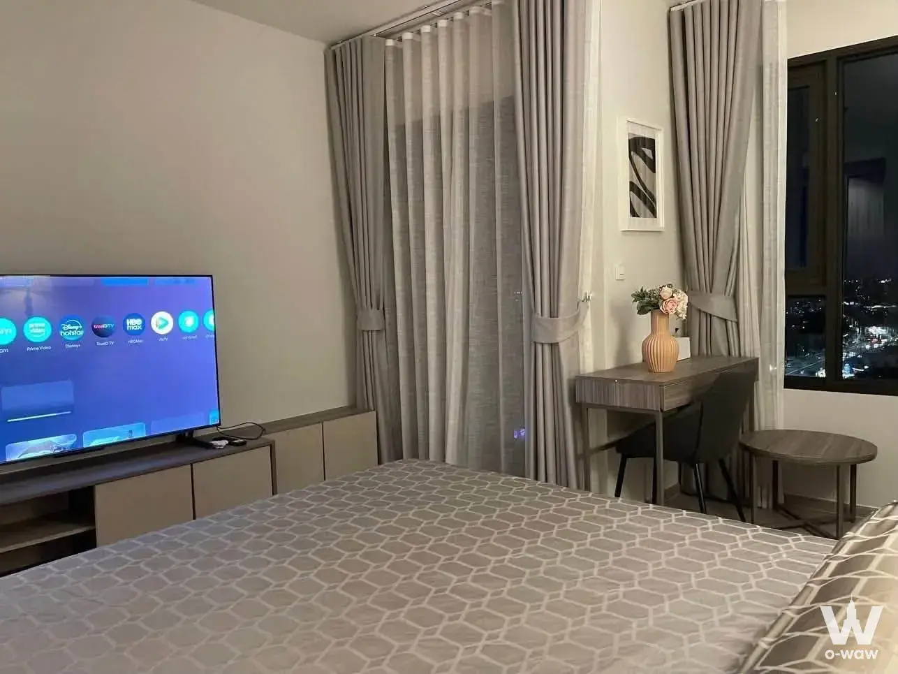 Life Sathorn Sierra 1-bed condo bedroom featuring smart TV, grey duvet, and night skyline view
