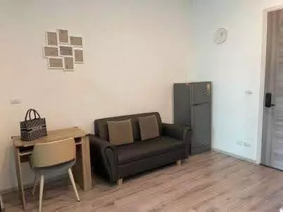 Compact 1-bed studio in Ramkhamhaeng featuring brown sofa, gallery wall art and wooden desk