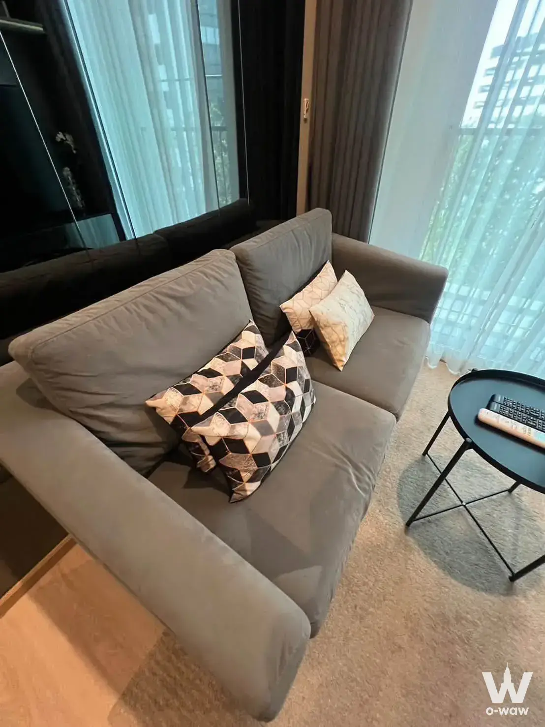 Living room with grey sofa and balcony access in Noble Revolve Ratchada 2