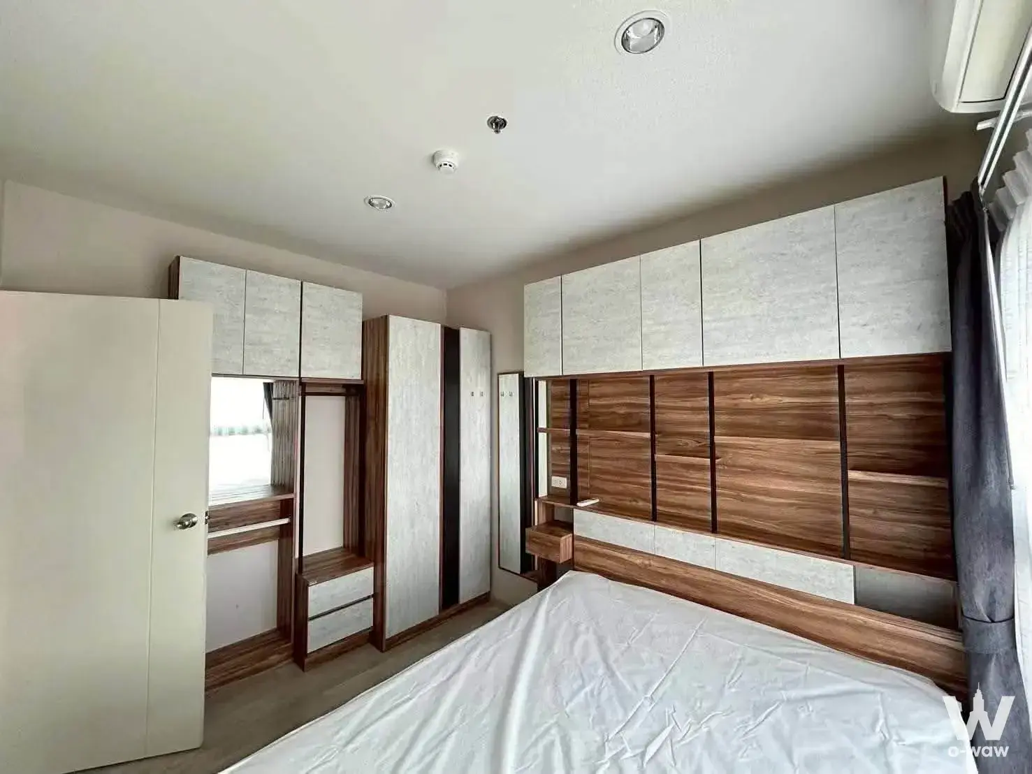 Built-in wardrobe with walnut panels and mirror in a 2-bed condo for rent at The Privacy Rama 9
