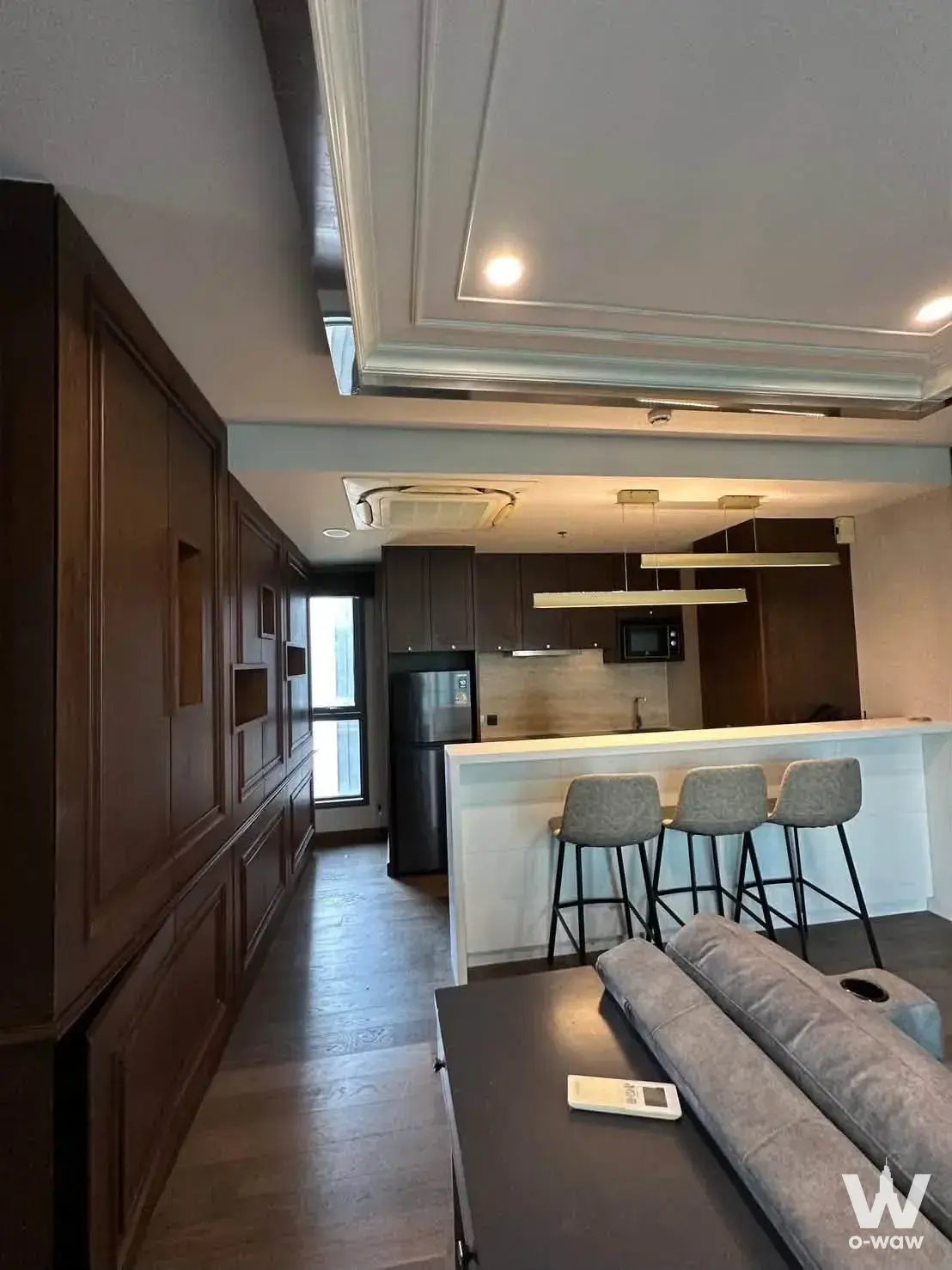 Modern open-plan living and kitchen with dark wood accents in Ideo Q Siam-Ratchathewi 2-bed condo