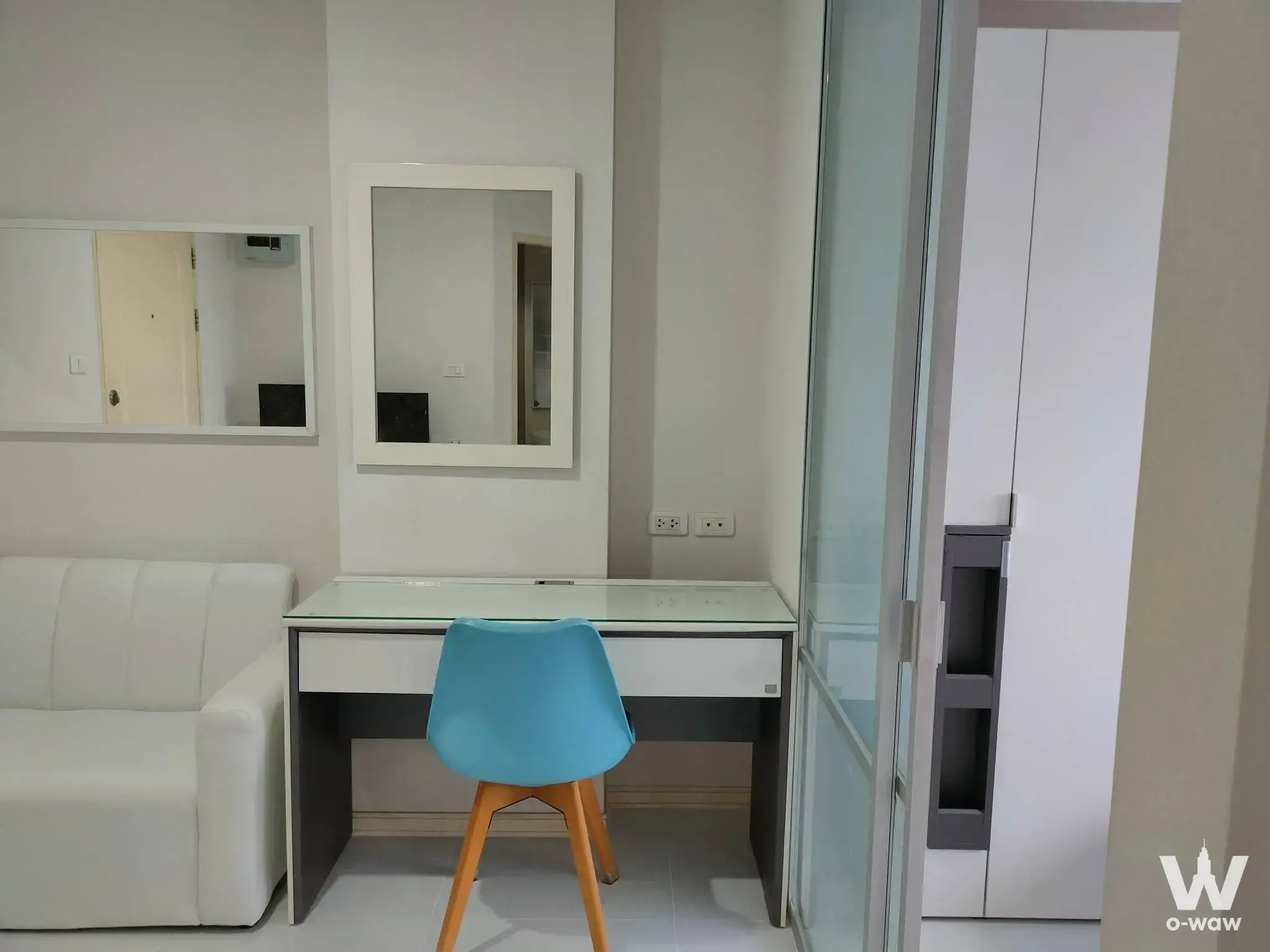 Studio workspace in a Lumpini Rangsit condo with white desk, blue chair and frosted glass partition