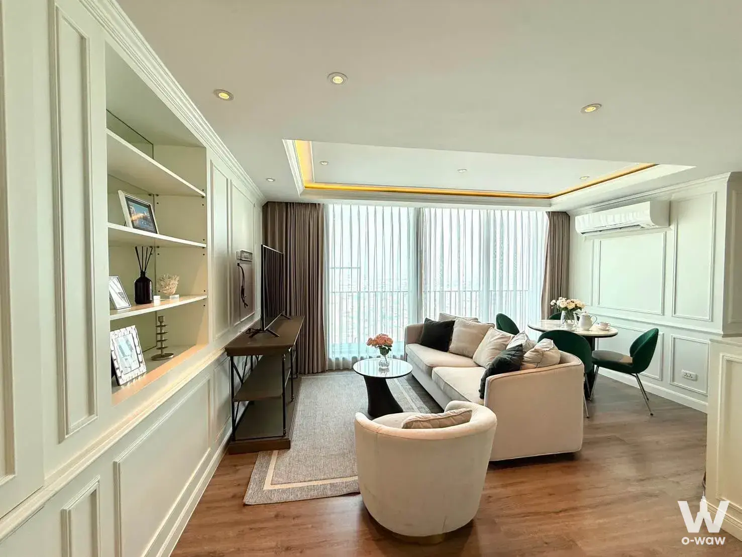 2-bed condo for rent in C Ekkamai Condominium with cream wainscoting, green velvet chairs, and city view