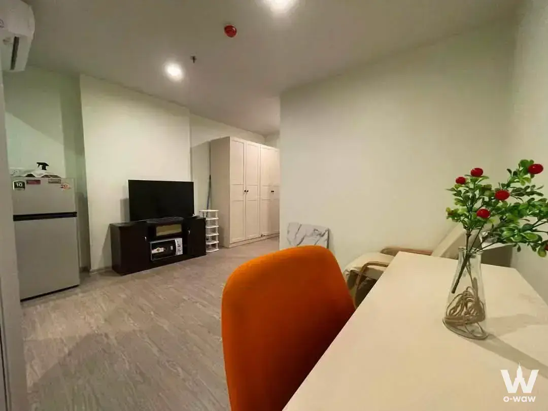 Furnished 1-bed Regent Home Bangna living room with grey laminate floors and bright orange dining chair