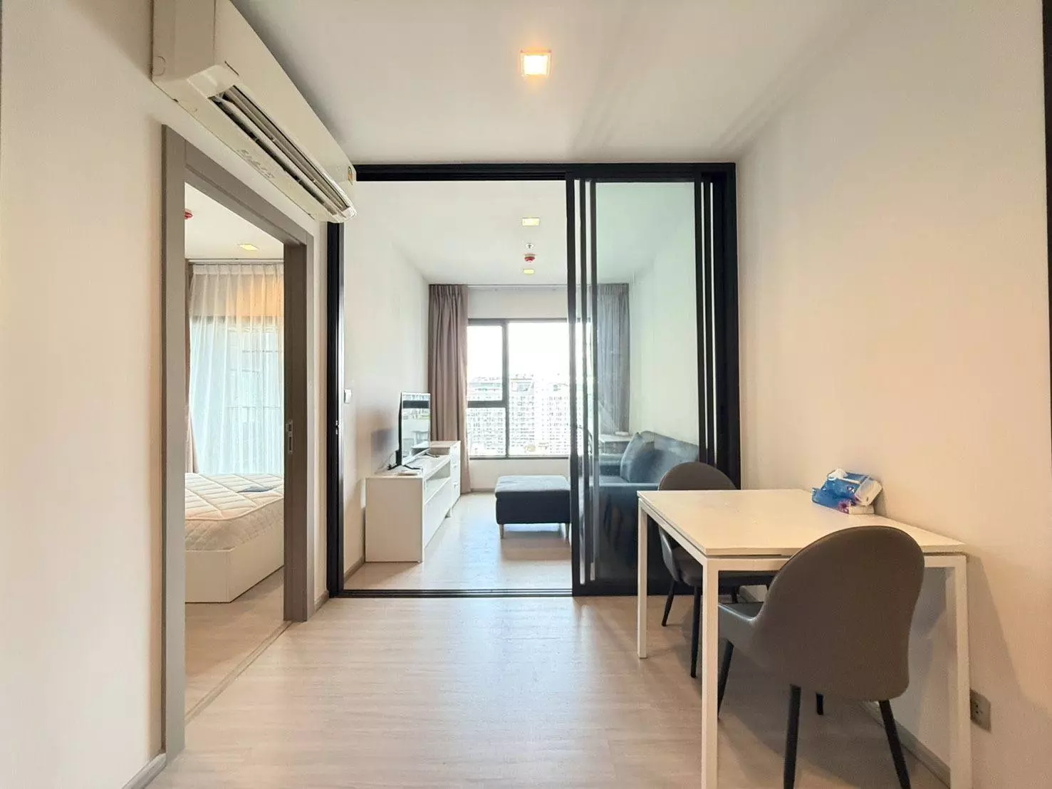 Open-plan condo in Life Asoke featuring a glass partition, dining set, and city skyline view