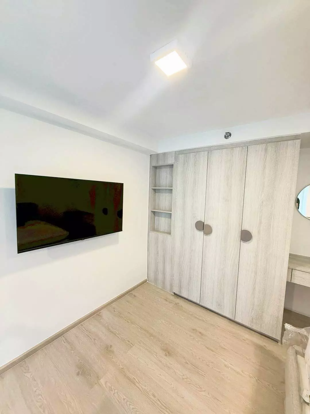 Minimalist bedroom with built-in grey wardrobes and wall-mounted TV in COBE Kaset-Sripatum condo