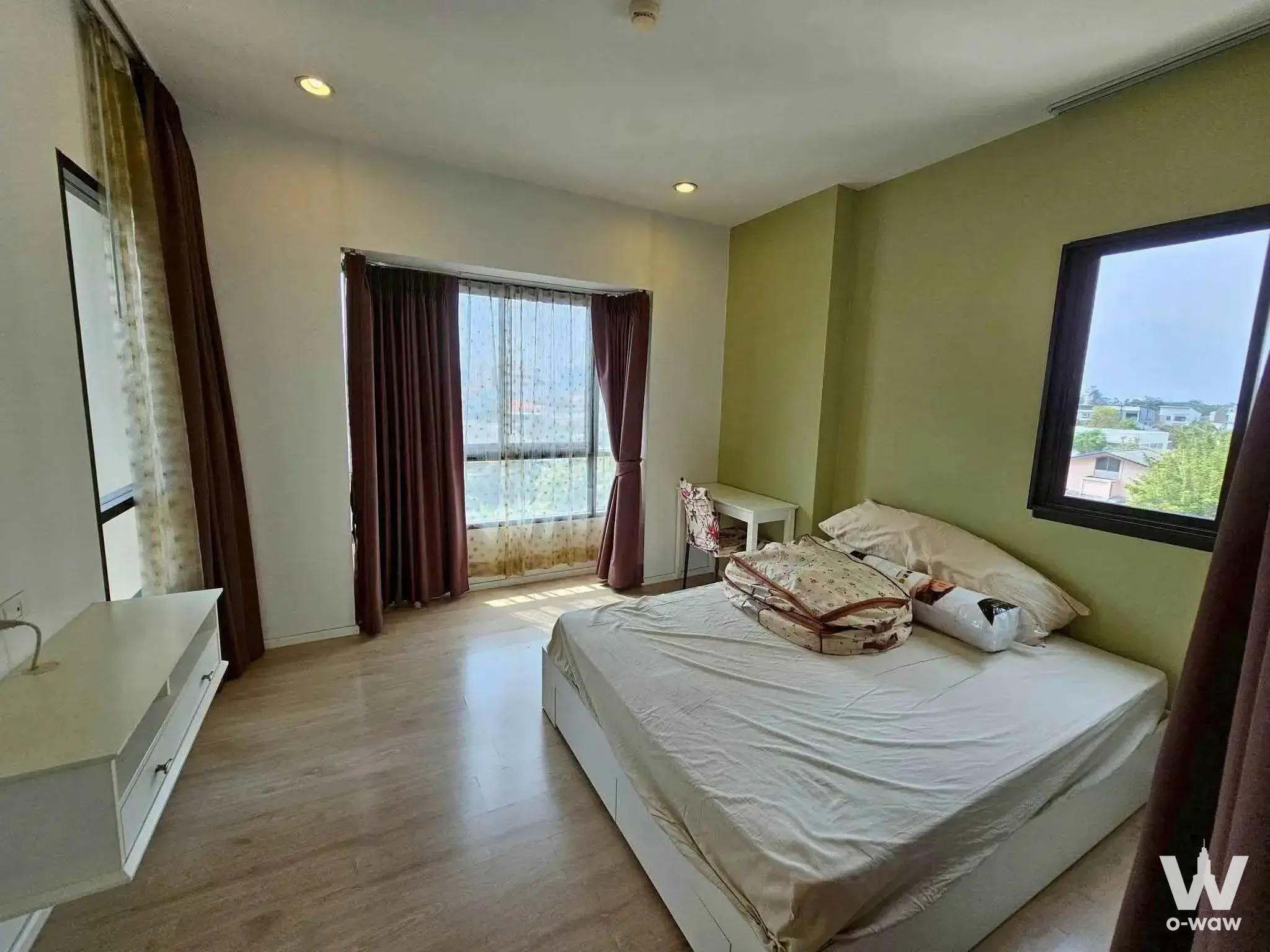Bedroom in a 2-bed condo for rent in S1 Rama 9 featuring olive green accent wall and balcony access